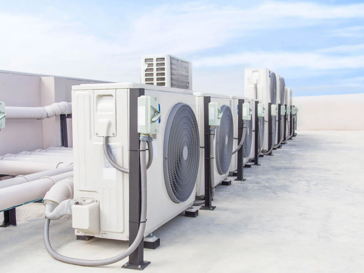 Heat pumps on a roof with a blue sky and light clouds in the background