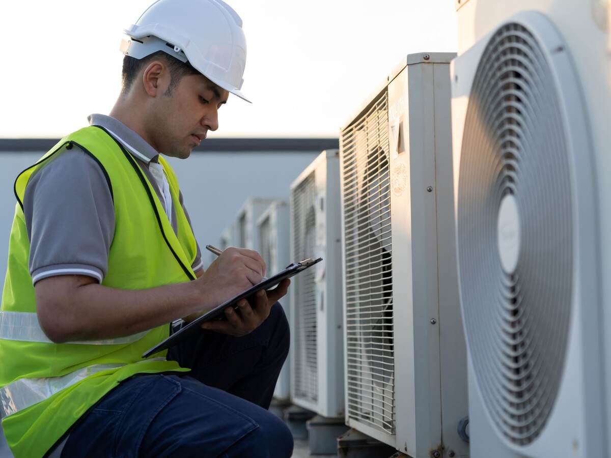 Man inspecting an outdoor unit of air conditioner