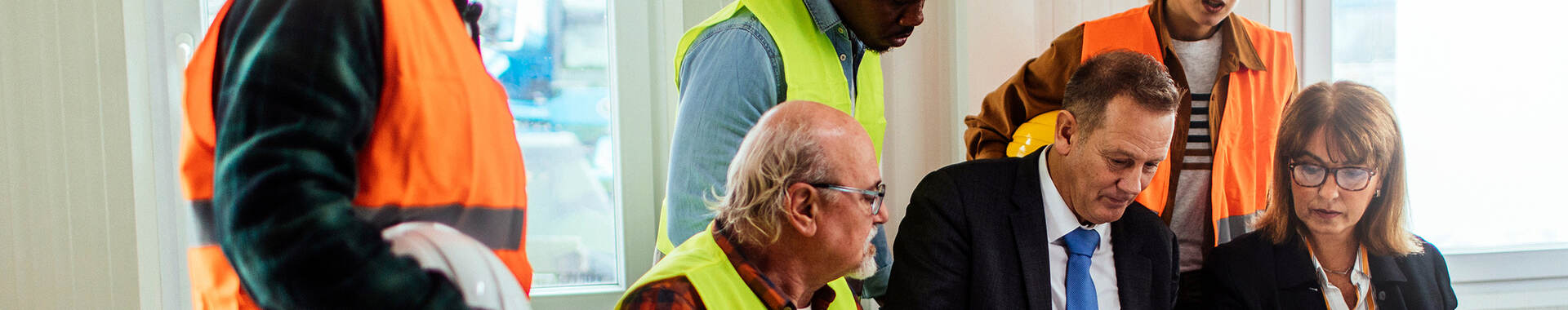 People in safety gear consulting with people in suits