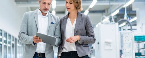 Two workers collaborating on a device while walking